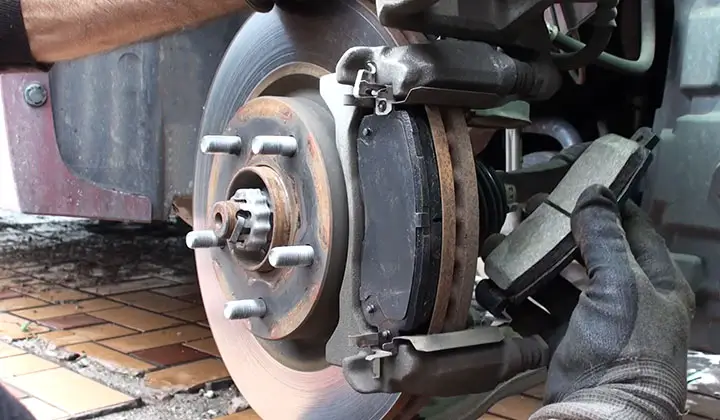 Position a new pair of brake pads over each disk